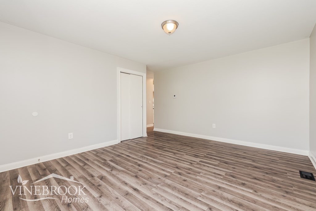 A room with wooden flooring and a doorway leading to another room.