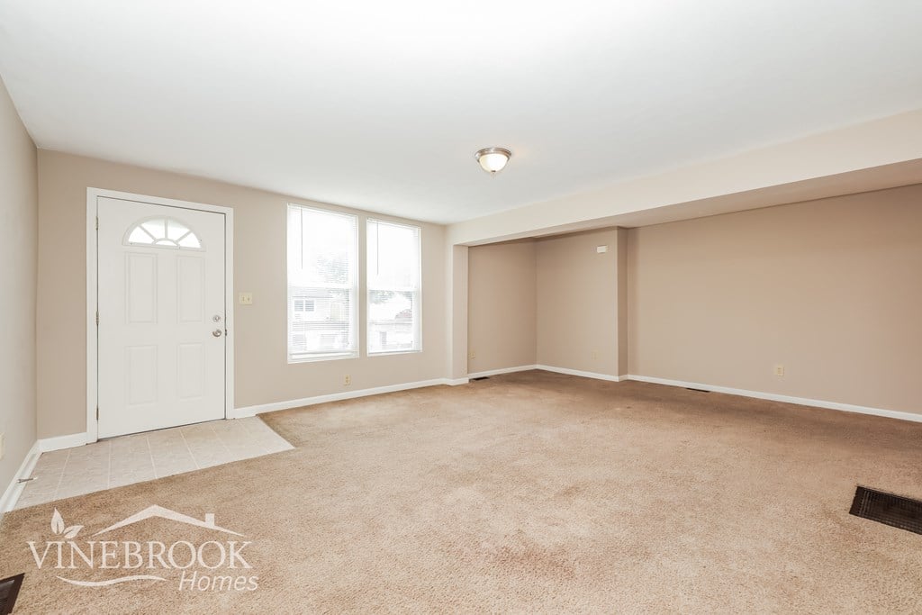 A room with a carpeted floor and a door on the left side.