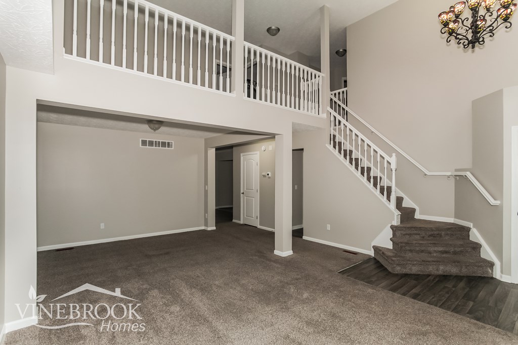 A spacious living room with a staircase leading to the upper floor.