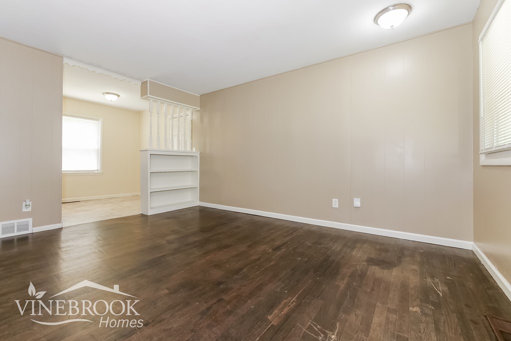 A room with wooden flooring and a white shelf unit.