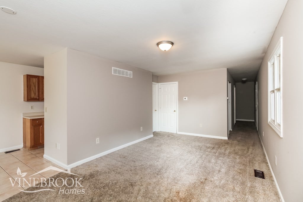 A spacious room with a carpeted floor and a ceiling light fixture.
