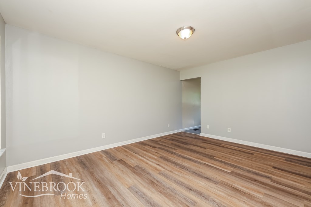 A room with wooden flooring and a white ceiling with a light fixture.