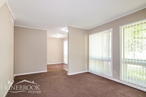 A room with a carpeted floor and a window with blinds.