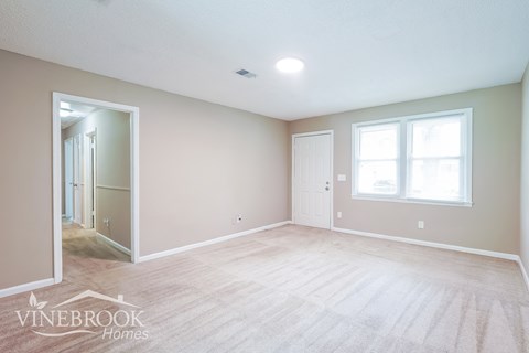 A spacious room with a carpeted floor and a large mirror on the wall.