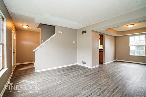 A spacious room with wood flooring and a staircase leading to another level.