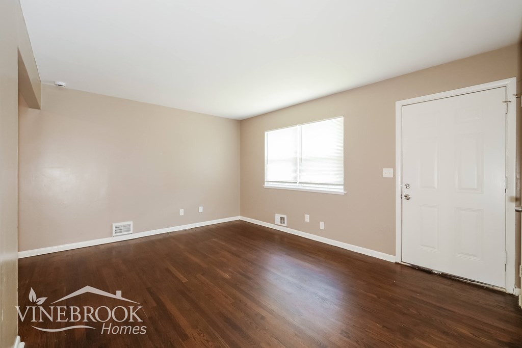 A room with a white door and a window with white blinds.