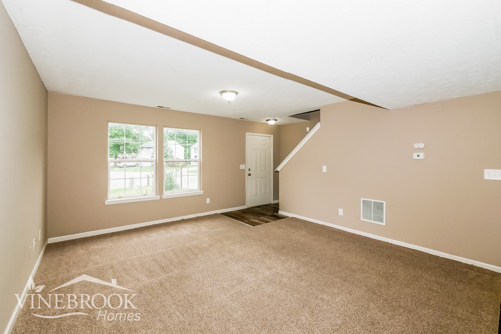 A room with a carpeted floor and a door leading to another room.