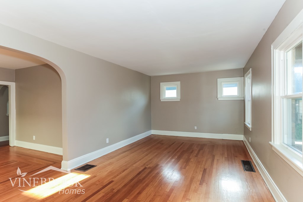 A room with wooden floors and a window on the right side.