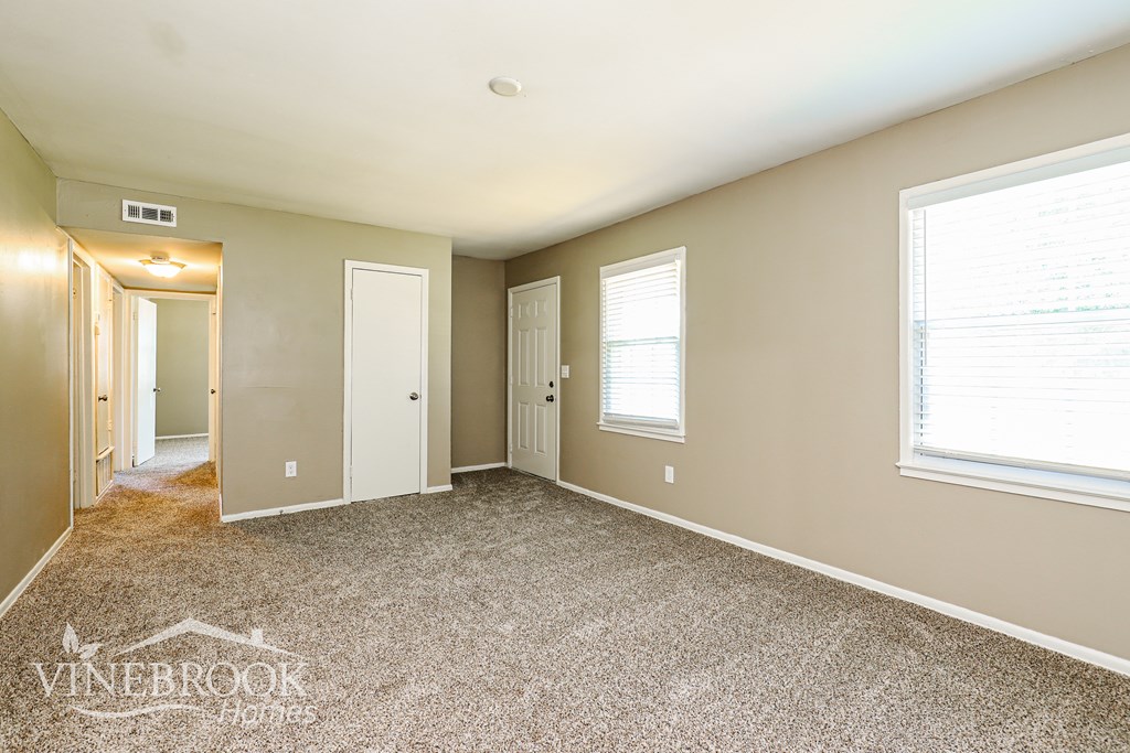 A room with a carpeted floor and a window with blinds.