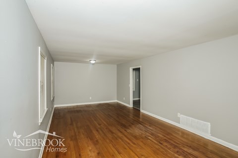 A room with wooden floors and white walls, with a door on the right side.