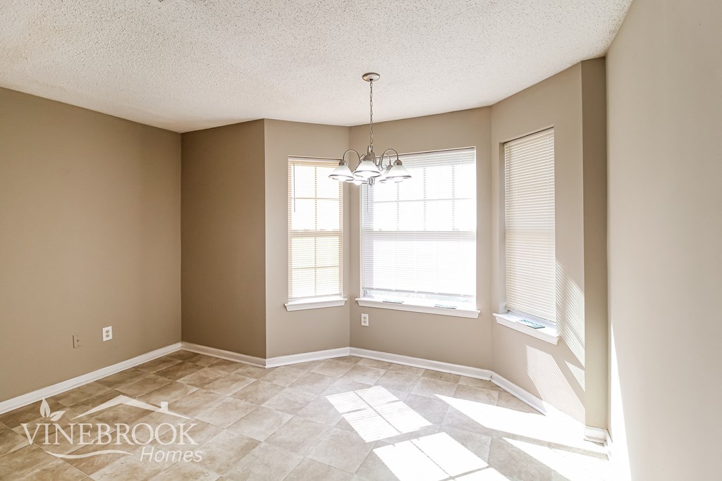 an empty dining room with two windows and a tile floor