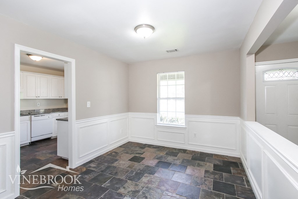 an empty dining room with white walls and a window