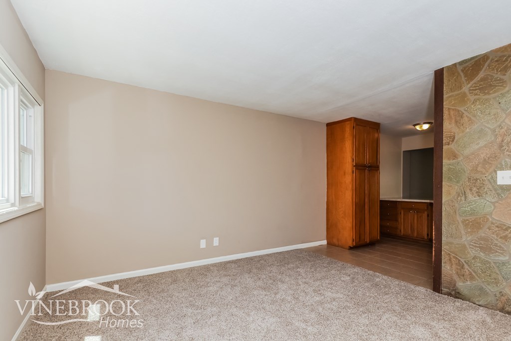the living room and dining room of a home with a stone wall