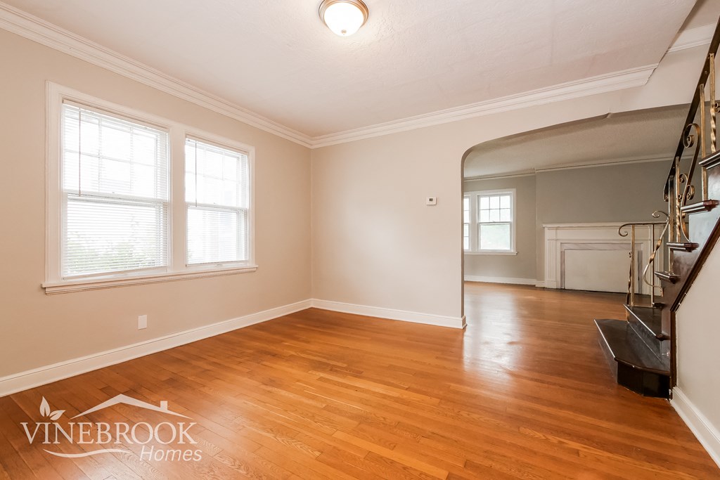 the living room and dining room of a house with wood floors and a staircase