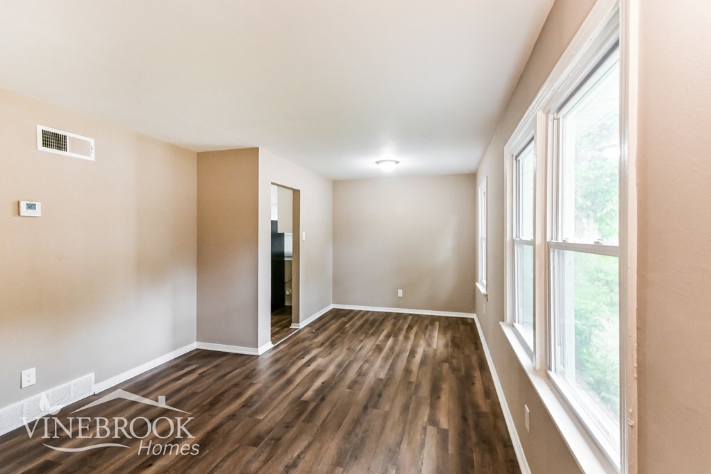 an empty living room with wood flooring and a large window