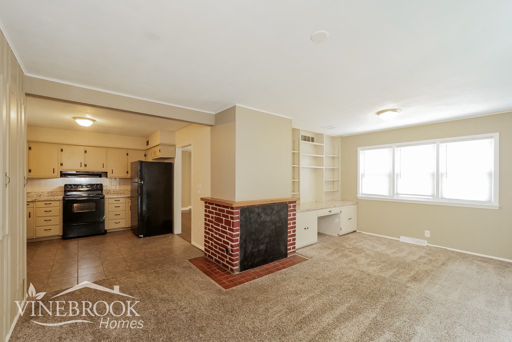 a kitchen and living room with a stove and refrigerator and a sink