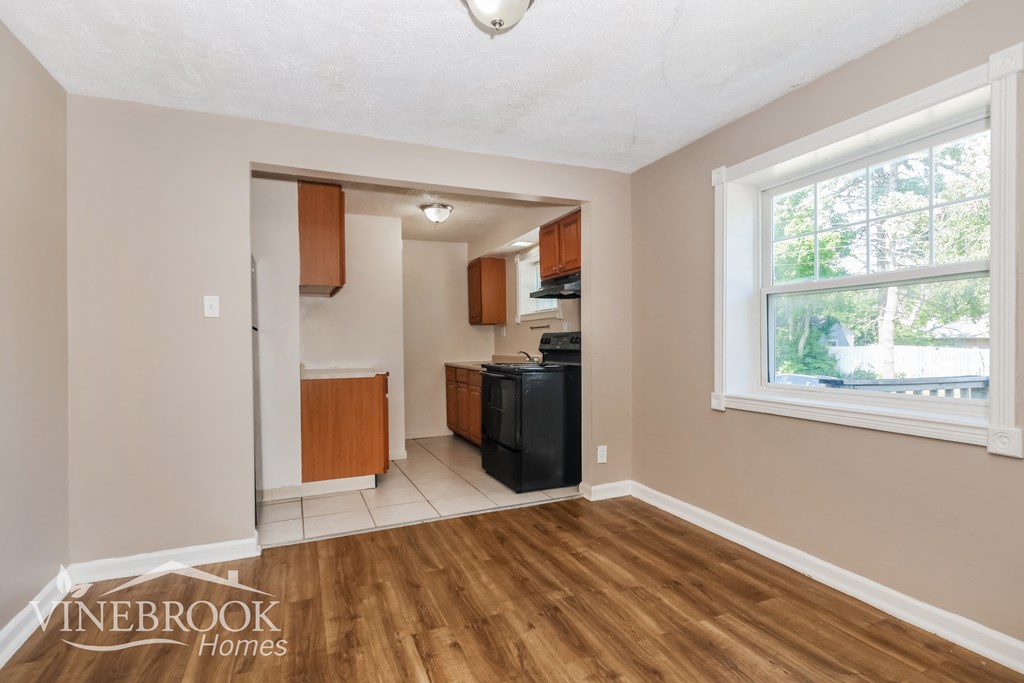 the living room and kitchen of an inherited home with wood flooring and a window