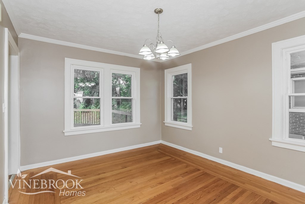 the living room of a home with a hardwood floor and three windows