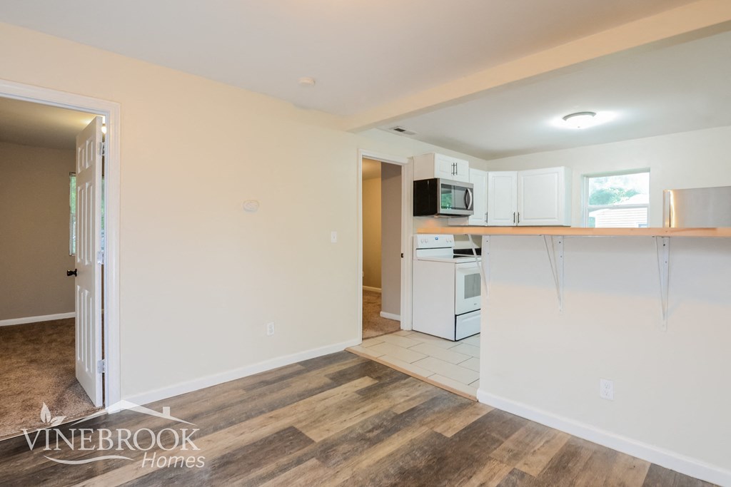 a renovated kitchen with white cabinets and a wood floor