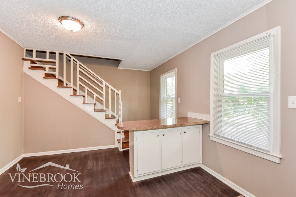 the living room of a home with a staircase and a counter and a window