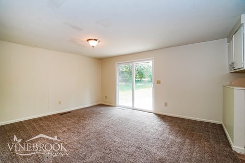 a living room with carpet and a door to a yard