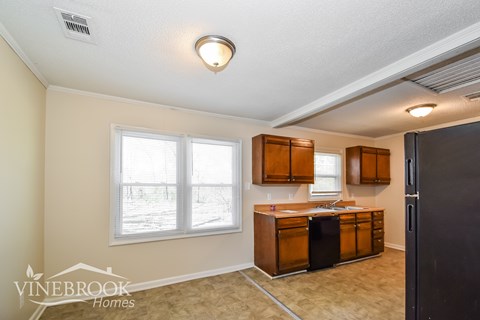 A kitchen with wooden cabinets and a black refrigerator.