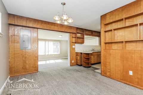 A living room with a grey carpet and wooden walls.