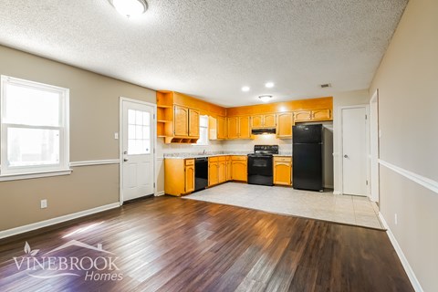 A kitchen with wooden floors and cabinets is shown.