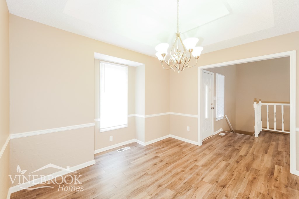 A room with wooden floors and a chandelier hanging from the ceiling.