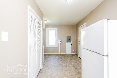 A white refrigerator is in a kitchen with beige walls and tile flooring.