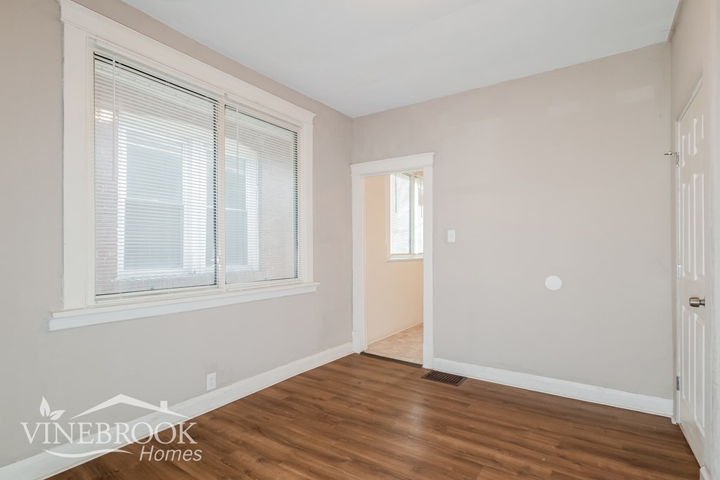 A room with wooden floors and a window with blinds.
