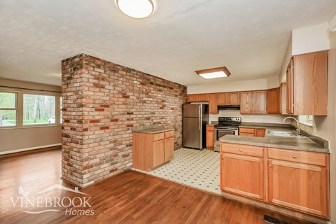 A kitchen with wooden cabinets and a brick column.