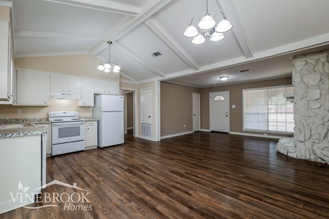 A kitchen with white appliances and wooden floors.