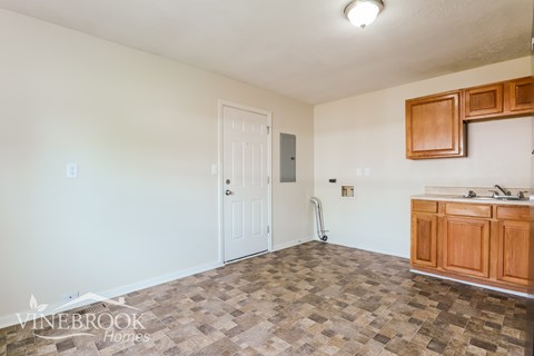 A room with a tiled floor and a kitchenette.