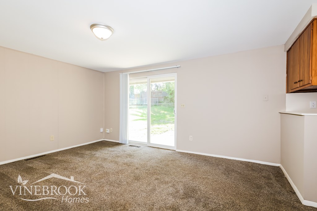 A room with a carpeted floor and a window with a view of the outside.