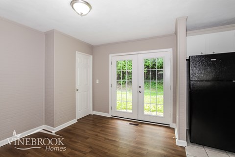 A room with a black fridge and a white door.
