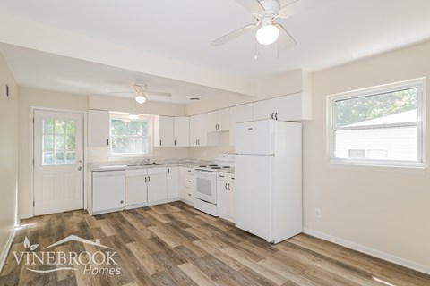 A kitchen with white appliances and wood flooring.