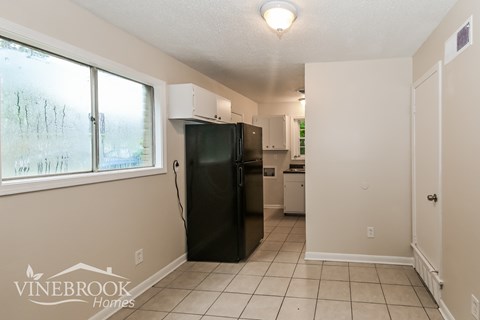 A kitchen with a black refrigerator and white cabinets.