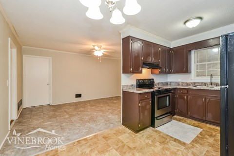 A kitchen with brown cabinets and a tiled floor.