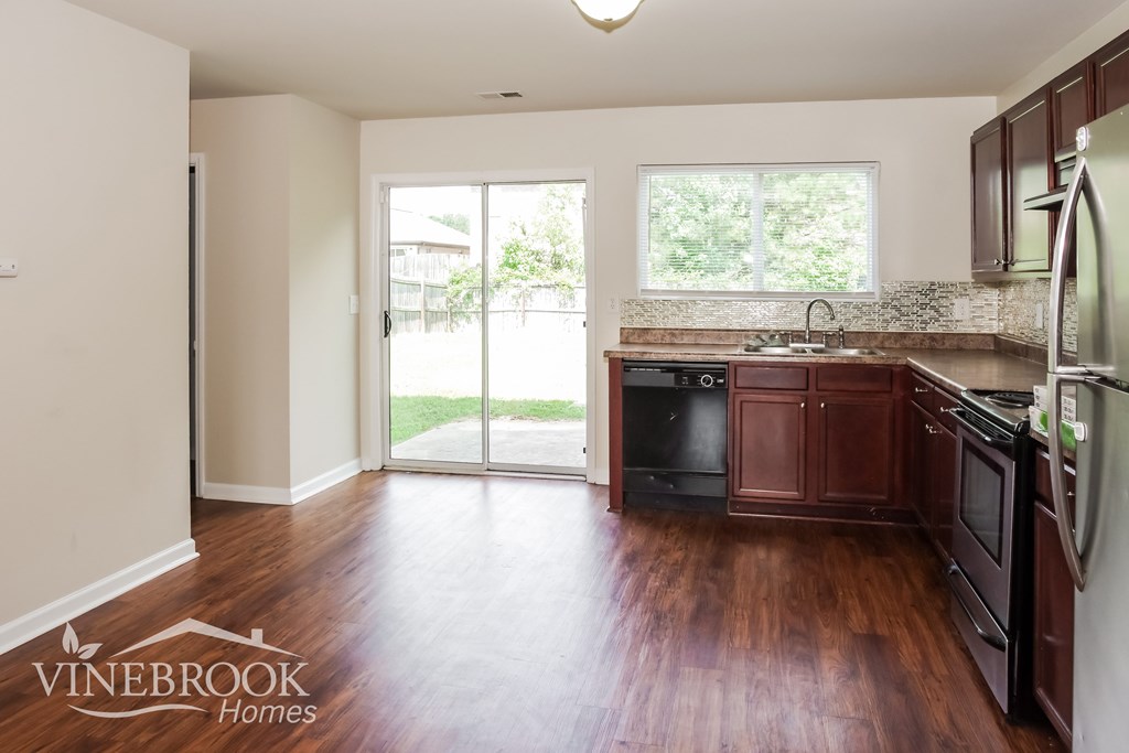 A kitchen with dark wood floors and a refrigerator on the right side.