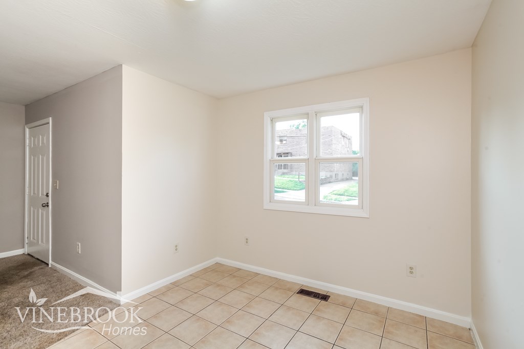 A room with a door and a window with a view of a building and trees outside.
