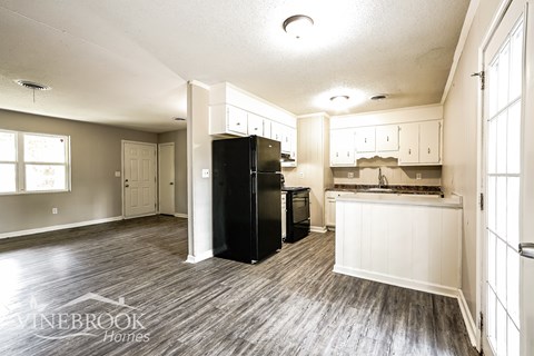 A kitchen with a black fridge and a sink with a window.