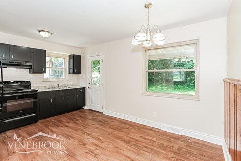 A kitchen with black cabinets and a window with a view of trees.