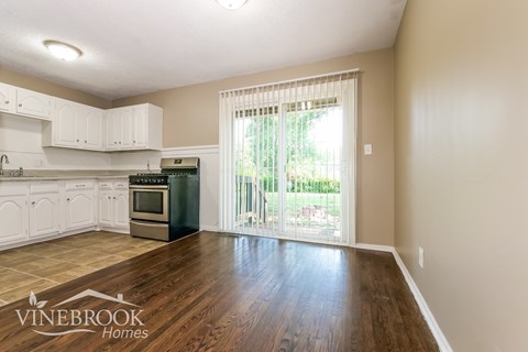 A kitchen with white cabinets and a wooden floor.