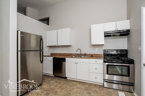 A kitchen with a refrigerator, oven, and cabinets.