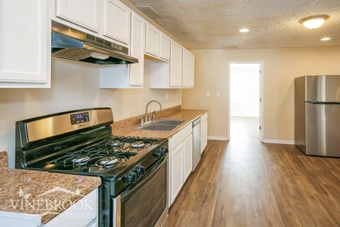 A kitchen with a stove top oven and a refrigerator.