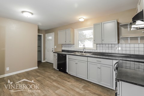 a kitchen with white cabinets and a black counter top and a sink