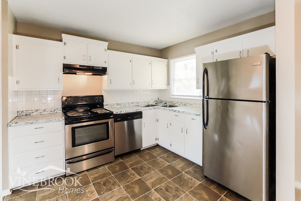 a renovated kitchen with stainless steel appliances and white cabinets