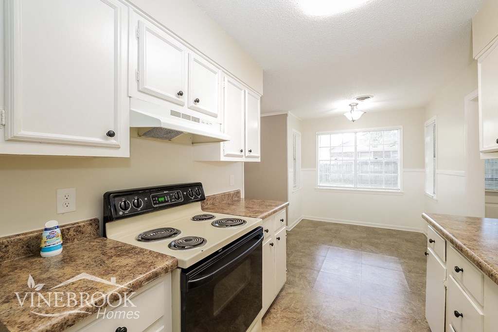 a kitchen with white cabinets and a stove and a window