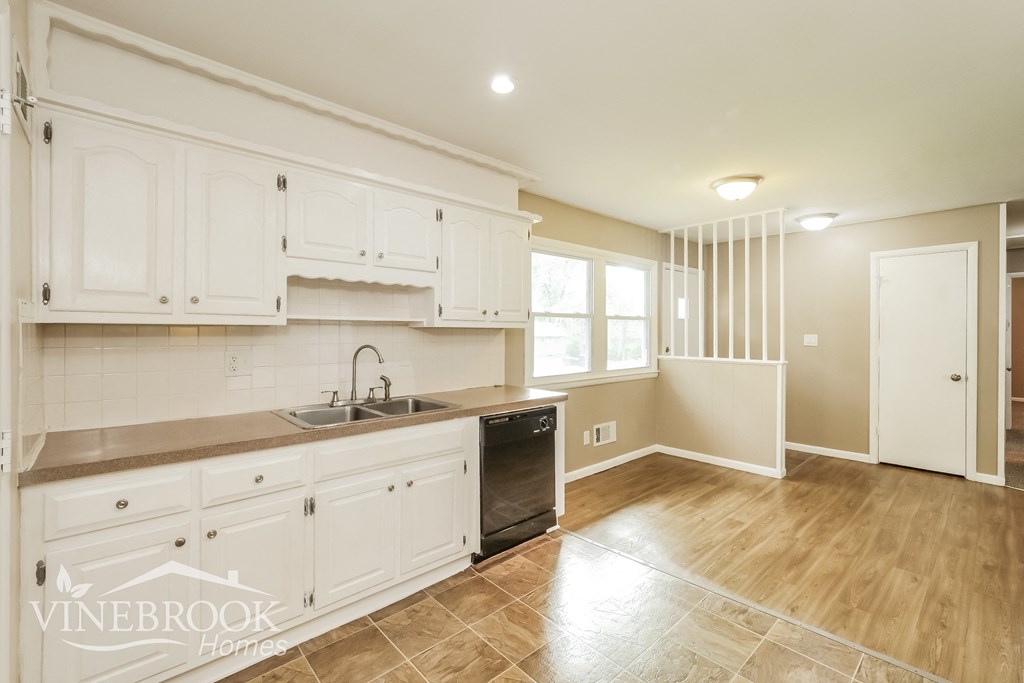 a white kitchen with white cabinets and a black dishwasher